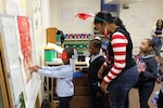 A DLA Troop Support volunteer helps children play games during the annual Children’s Holiday Party Dec. 12, 2019 in Philadelphia.