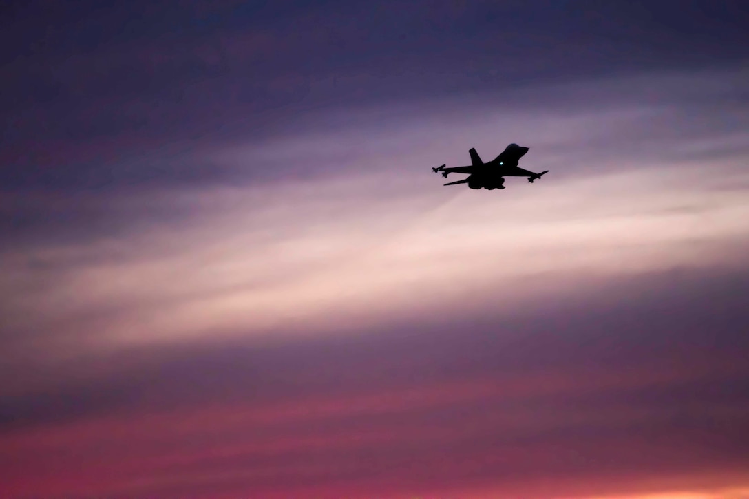 A plane flying through a purple sky.