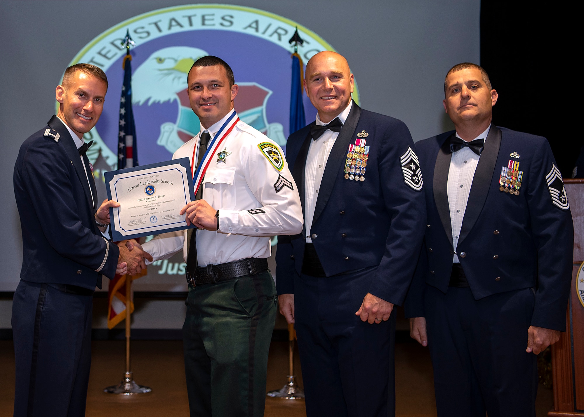 Hillsborough County Sherriff’s Office Cpl. Tommy Herr, accepts an Airman Leadership School (ALS) diploma from U.S. Air Force Col. Stephen Snelson, 6th Air Refueling Wing commander, during his ALS graduation, Dec. 4, 2019, at MacDill Air Force Base, Fla.