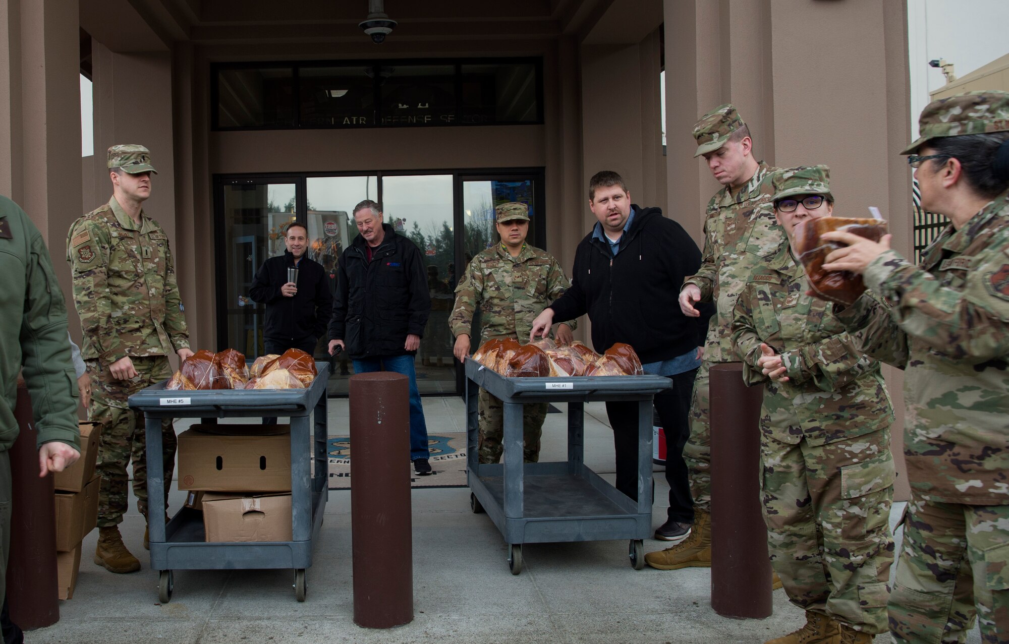 Western Air Defense Sector Airmen carry hams to a cart during Operation Ham Grenade at Joint Base Lewis-McChord, Wash., Dec. 17, 2019. More than 300 hams were donated to McChord Field Airmen by the Air Force Association McChord Field Chapter and Pierce Military Business Alliance. (U.S. Air Force photo by Senior Airman Tryphena Mayhugh)