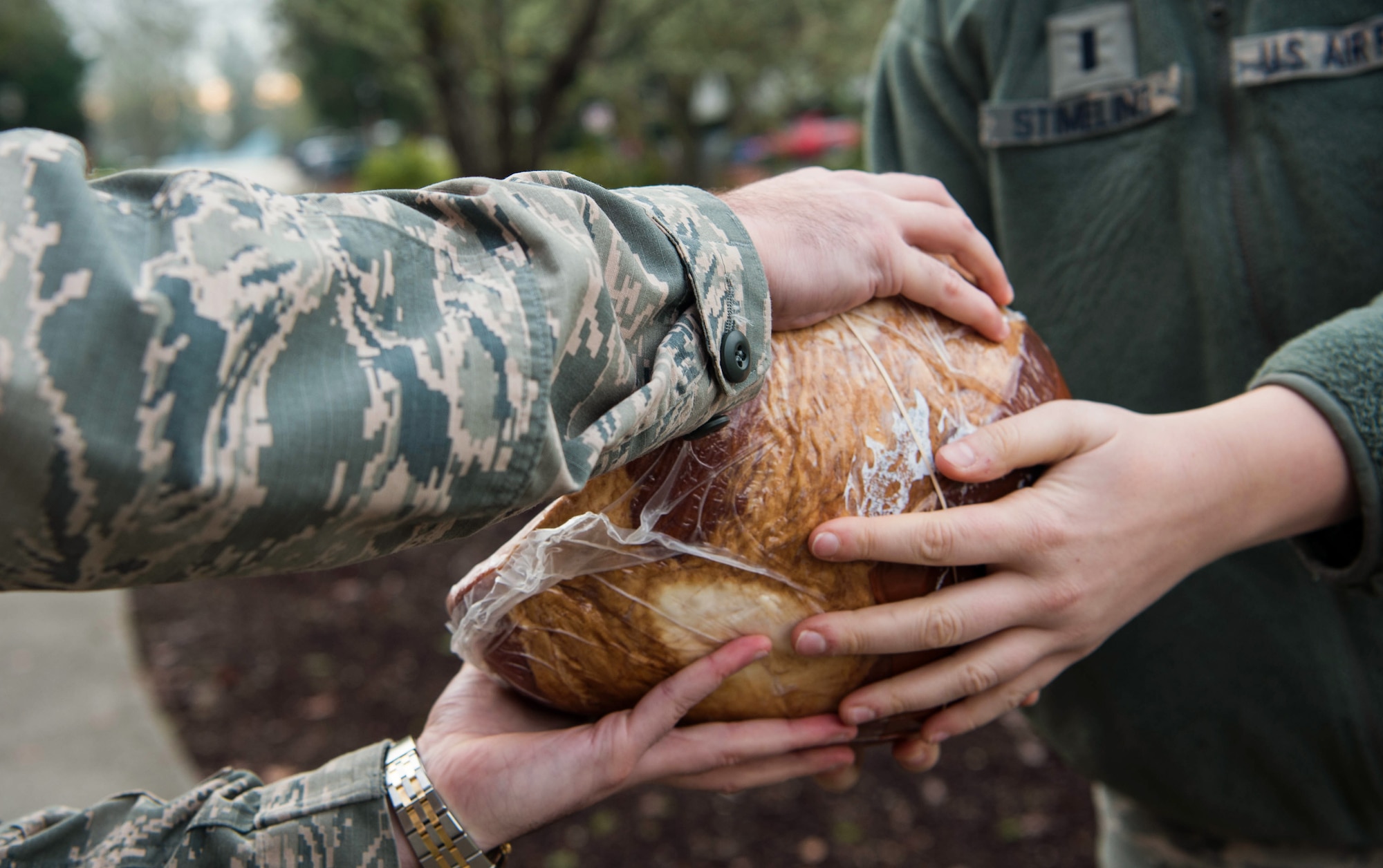 1st Lt. Lindsey Stimeling, 62nd Airlift Wing executive officer, hand a ham to a fellow Airmen during Operation Ham Grenade at Joint Base Lewis-McChord, Wash., Dec. 17, 2019. The Air Force Association McChord Field Chapter and Pierce Military Business Alliance donated the hams for Team McChord Airmen and their families. (U.S. Air Force photo by Senior Airman Tryphena Mayhugh)