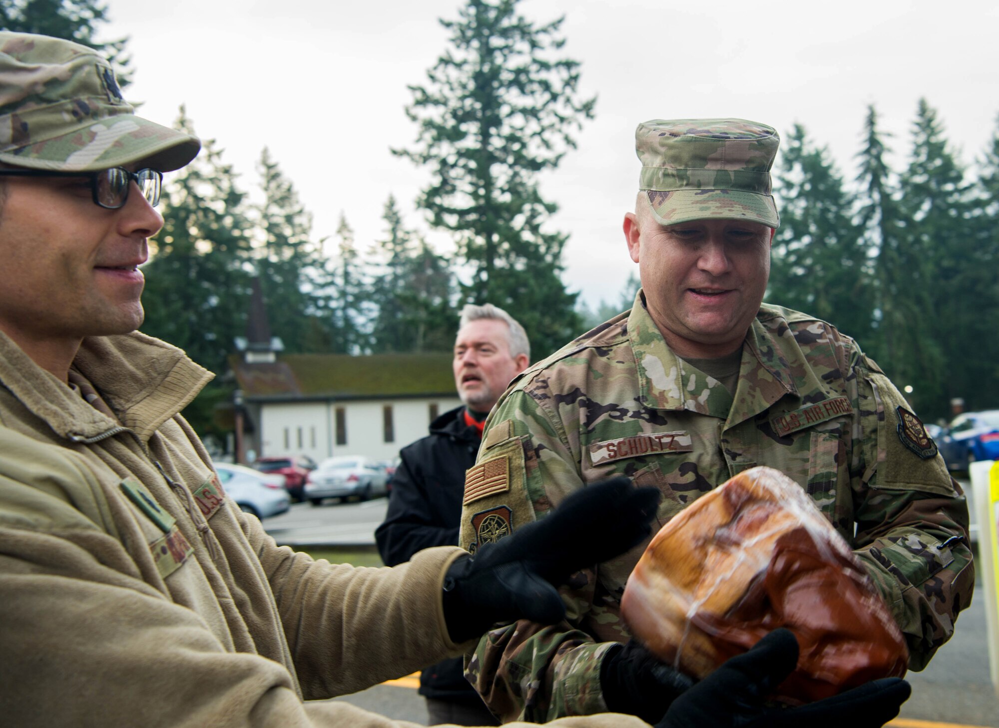 Chief Master Sgt. Rob Schultz, 62nd Airlift Wing command chief, passes along a ham during Operation Ham Grenade at Joint Base Lewis-McChord, Wash., Dec. 17, 2019. More than 300 ham were donated to Team McChord Airmen for them and their families during the holidays. (U.S. Air Force photo by Senior Airman Tryphena Mayhugh)