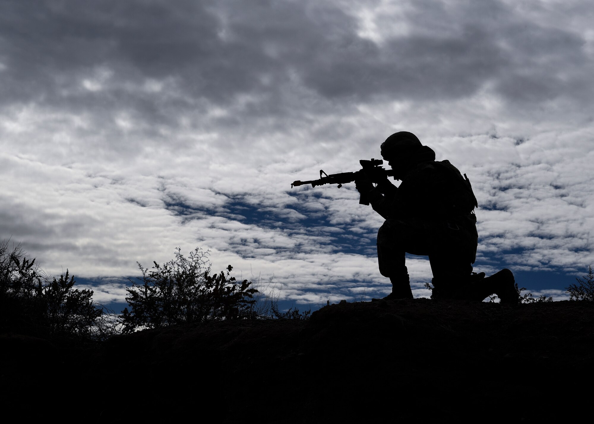 A security forces member aims his weapon at opposing forces during training.