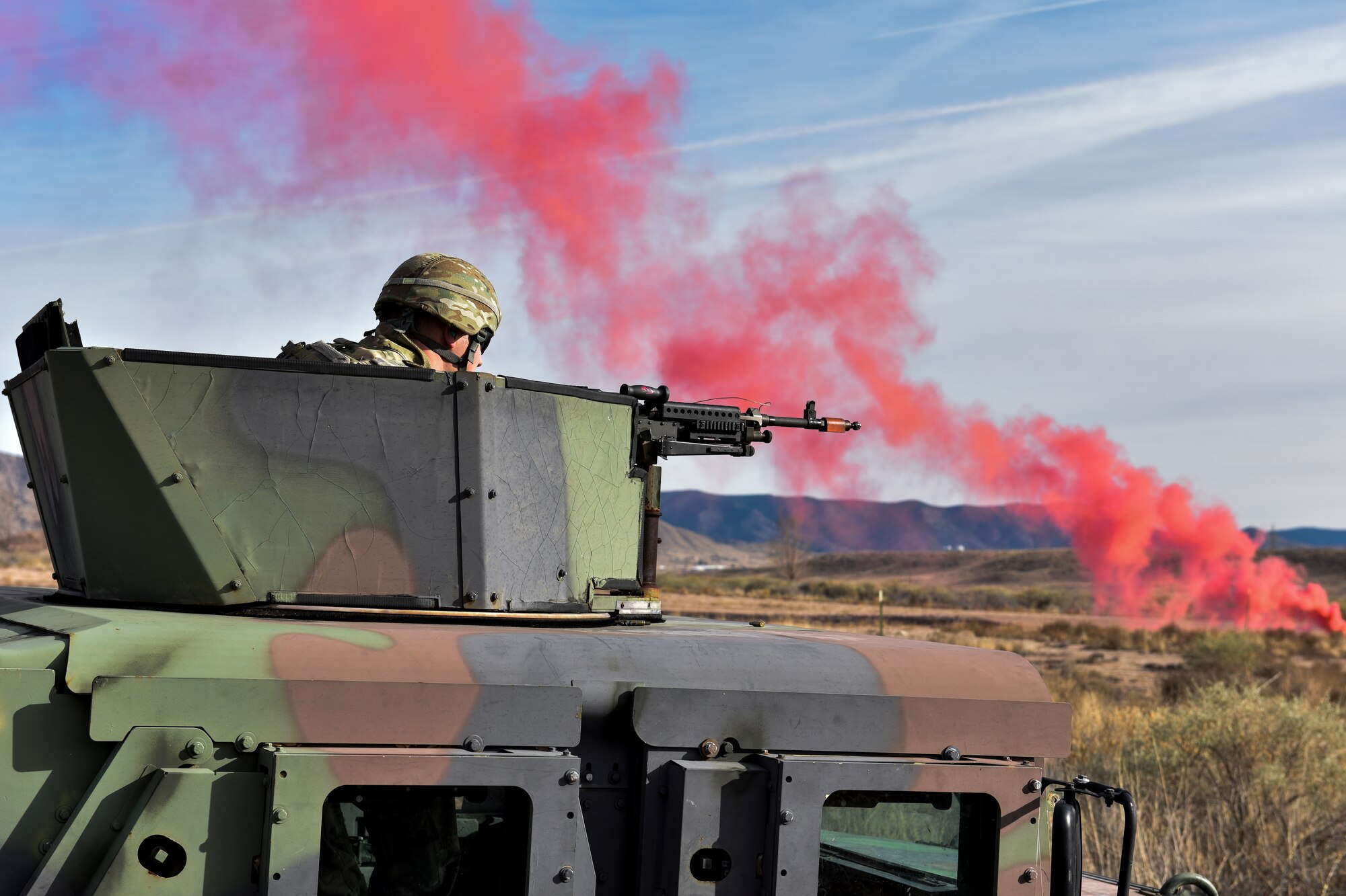 A security forces member in a humvee aims a M240B machine gun at opposing forces during training.