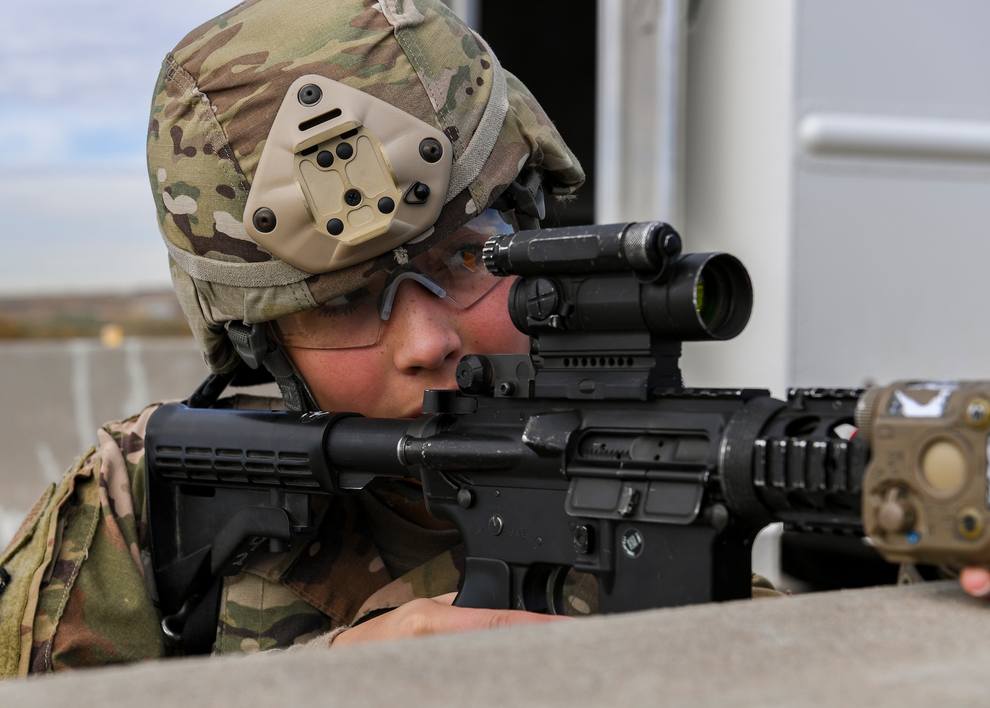 A security forces member looks down her scope.