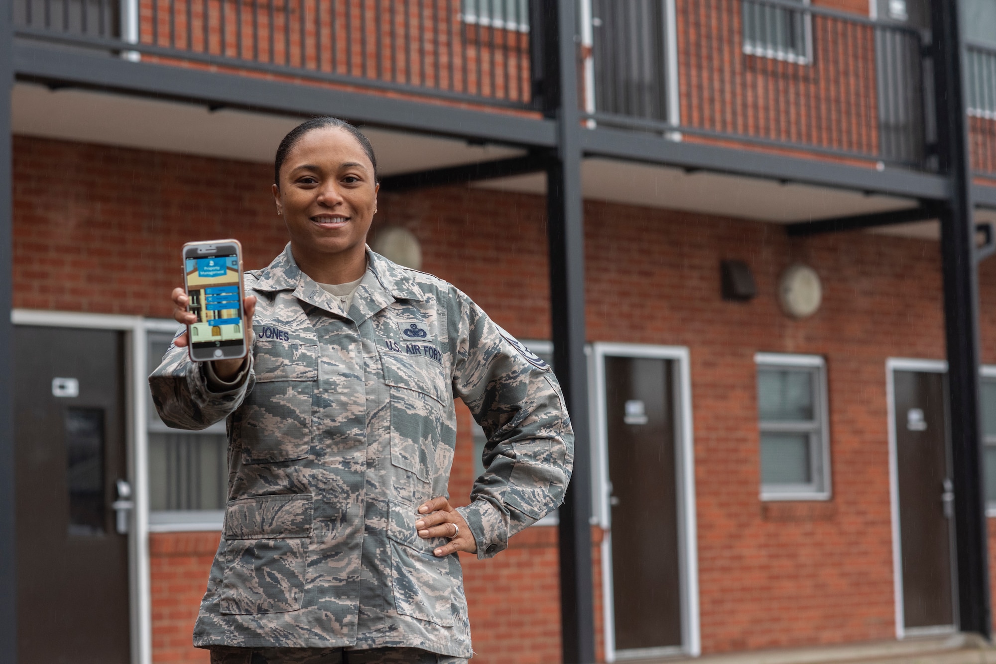 Master Sgt. Erika Jones, 100th Civil Engineer Squadron airmen dorm leader superintendent, displays the dorm app she designed at RAF Mildenhall, England, Dec. 17, 2019. Airmen living in the dorms can benefit from the improved process the app provides for submitting work order requests. (U.S. Air Force photo by Airman 1st Class Joseph Barron)