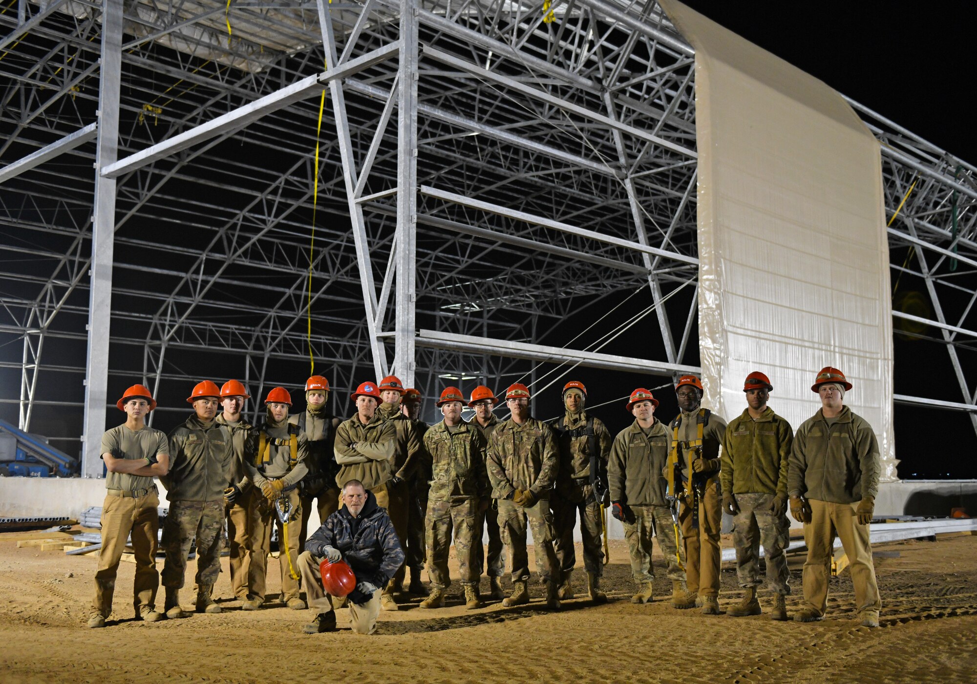 U.S. Airmen deployed with the 819th Expeditionary Rapid Engineer Deployable Heavy Operational Repair Squadron Engineer team pause for a photo while constructing a new hangar at Nigerien Air Base 201, Niger, Dec. 13, 2019. In Niger, deployed RED HORSE teams are continually improving base infrastructure and building new facilities for current and future missions. (U.S. Air Force photo by Staff Sgt. Alex Fox Echols III)