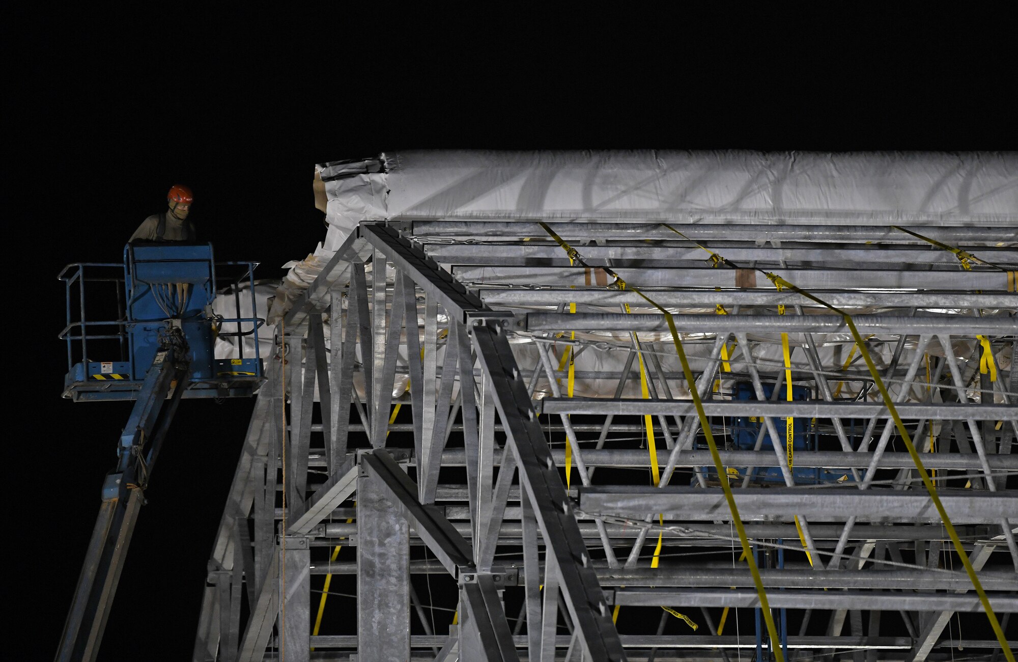 A U.S. Airman deployed with the 819th Expeditionary Rapid Engineer Deployable Heavy Operational Repair Squadron Engineer team prepares to roll out a side panel on a new hangar at Nigerien Air Base 201, Niger, Dec. 13, 2019. In Niger, deployed RED HORSE teams are continually improving base infrastructure and building new facilities for current and future missions. (U.S. Air Force photo by Staff Sgt. Alex Fox Echols III)