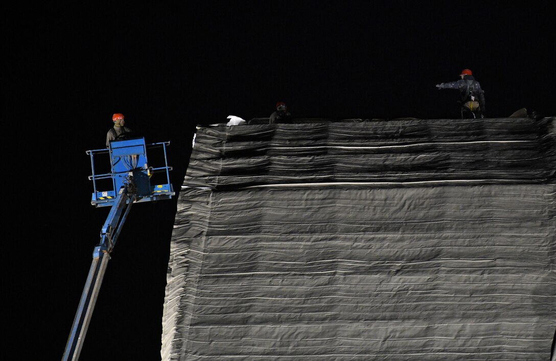 U.S. Airmen deployed with the 819th Expeditionary Rapid Engineer Deployable Heavy Operational Repair Squadron Engineer team roll out a side panel on a new hangar at Nigerien Air Base 201, Niger, Dec. 13, 2019. In Niger, deployed RED HORSE teams are continually improving base infrastructure and building new facilities for current and future missions. (U.S. Air Force photo by Staff Sgt. Alex Fox Echols III)