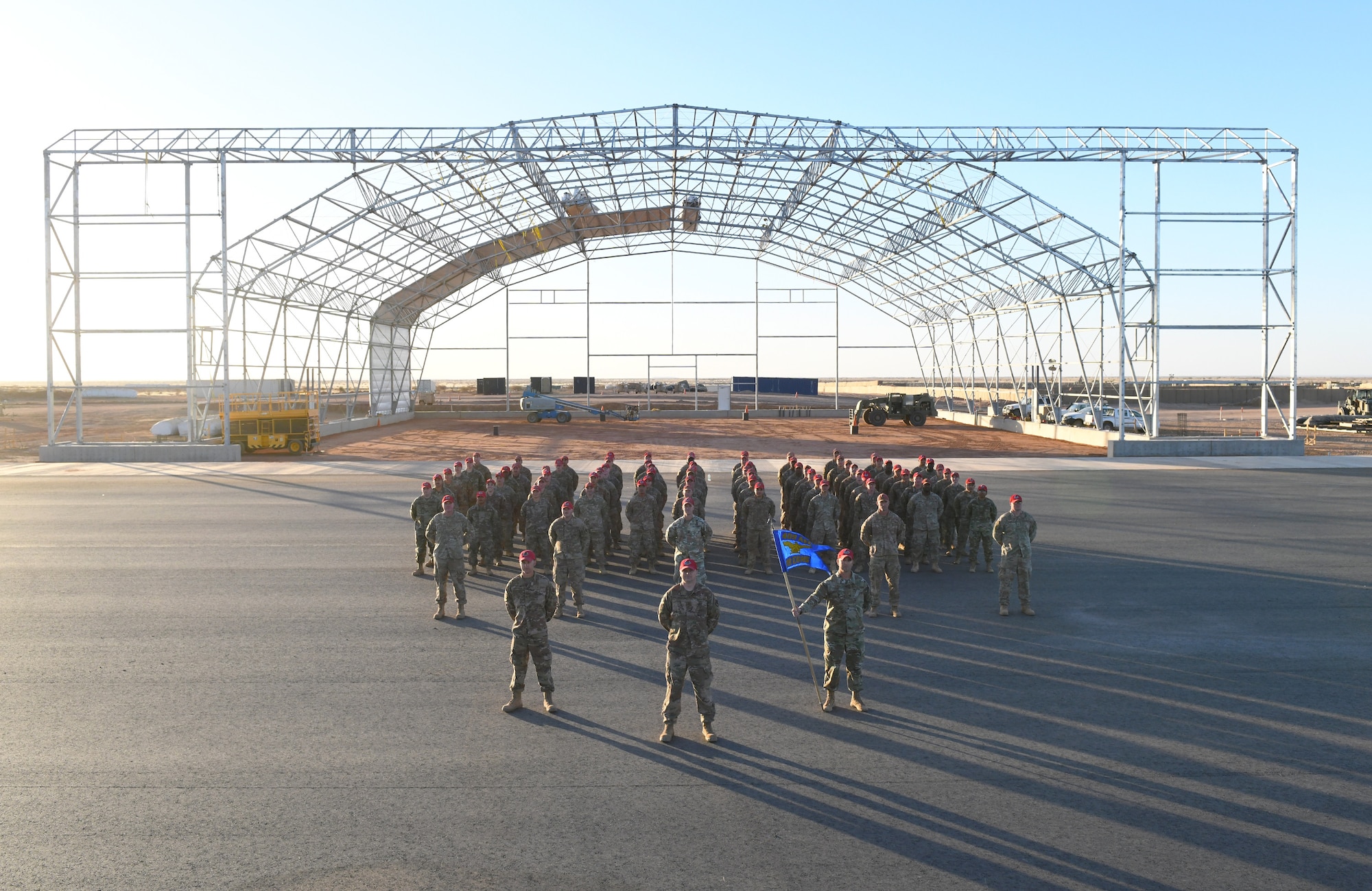 The 819th Expeditionary Rapid Engineer Deployable Heavy Operational Repair Squadron Engineer team stands in formation at the construction site of a new hangar at Nigerien Air Base 201, Niger, Dec. 16, 2019. In Niger, deployed RED HORSE teams are continually improving base infrastructure and building new facilities for current and future missions. (U.S. Air Force photo by Staff Sgt. Alex Fox Echols III)