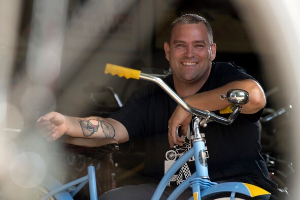 Photo of an Airman displaying a tattoo of his father’s bicycle