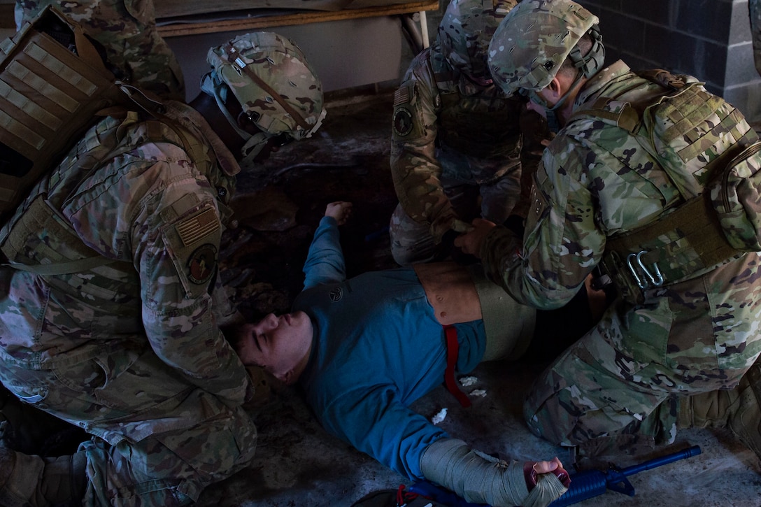 Photo of Airmen assess a simulated victim during the Combat Lifesavers Course.