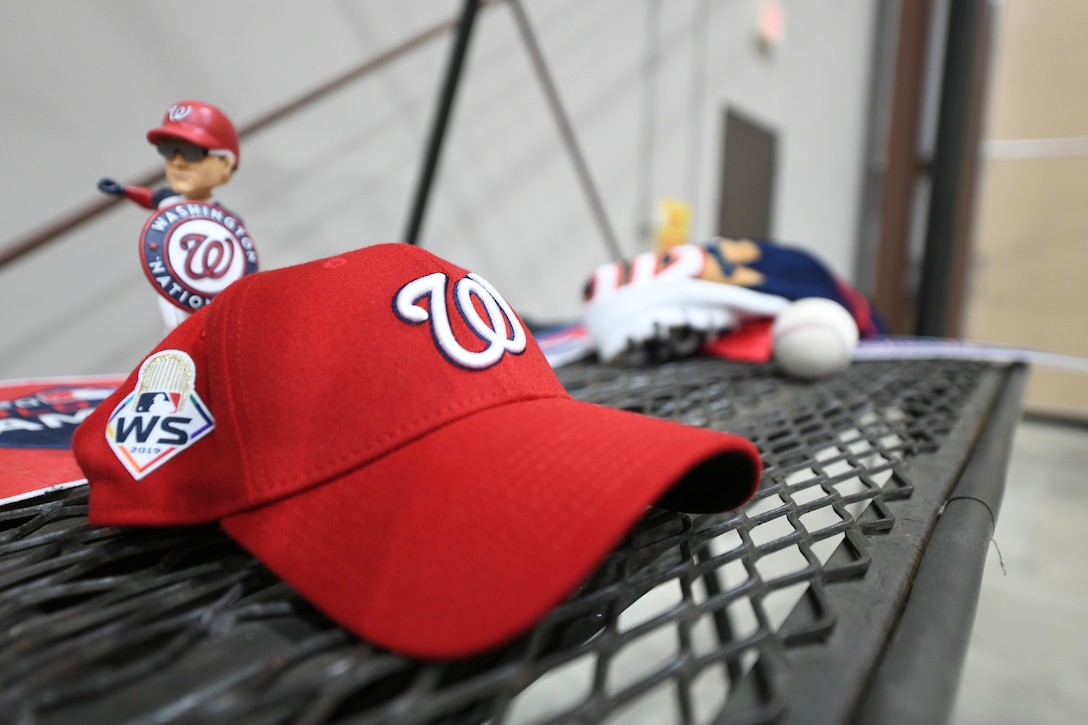 A Washington Nationals hat is displayed next to other team souveniers during a World Series trophy display event at Joint Base Andrews, Md., Dec. 17, 2019. Ryan Zimmerman, Washington Nationals first baseman, toured parts of the base including the 1st Helicopter Squadron and the 113th Wing, District of Columbia Air National Guard. (U.S. Air Force photo by Airman 1st Class Spencer Slocum)