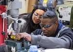 A Continuous Training and Development program instructor watches a worker check the level on a drilling project.