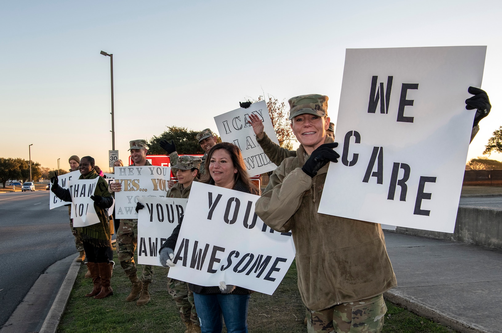 37th Training Wing military and civilian members hold positive messages of support at base gates during the morning inbound commute as part of their new initiative, “We Care,” at Joint Base San Antonio-Lackland, Texas, Dec. 18, 2019. The initiative involved 37th Training Wing military and civilian members spending the morning at various gates letting each person know that they stand together in support of those struggling with depression and thoughts of suicide by holding a positive message of support and handing out over 400 candy canes. If you are struggling with thoughts of suicide, please go directly to the Mental Health Clinic or to your closest Emergency Room. You can also reach the National Suicide Prevention Lifeline at 1-800-273-8255.