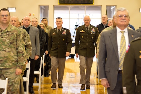 Two generals in green dress uniform walk down center isle.