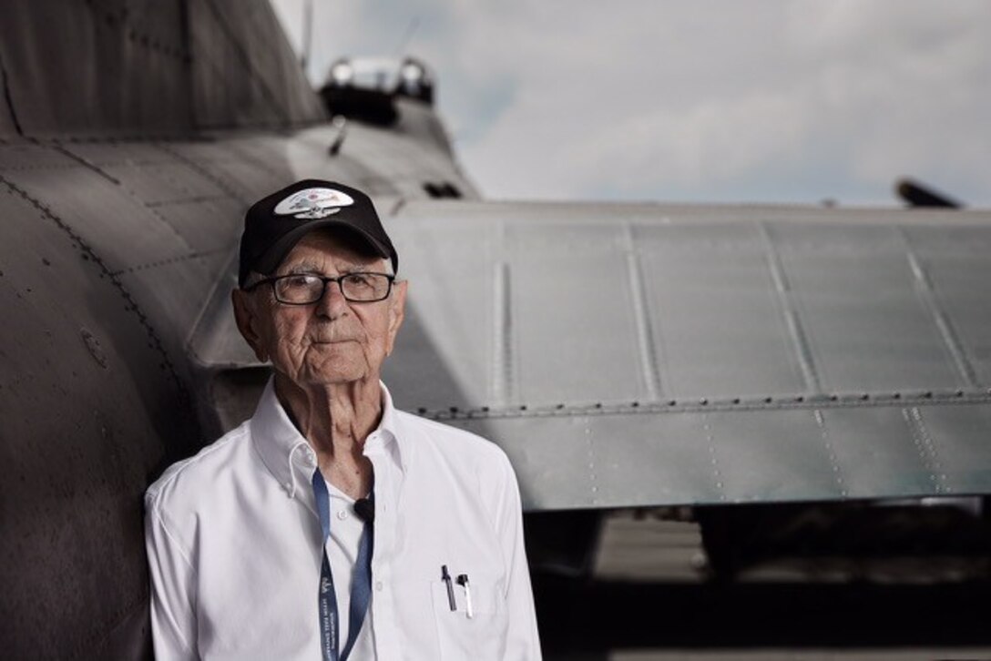 A man poses next to an aircraft.