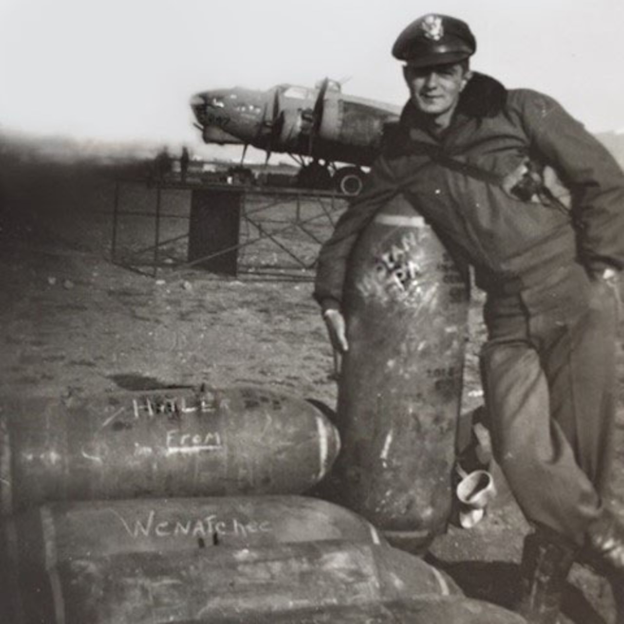 A man poses next to a big artillery shell.