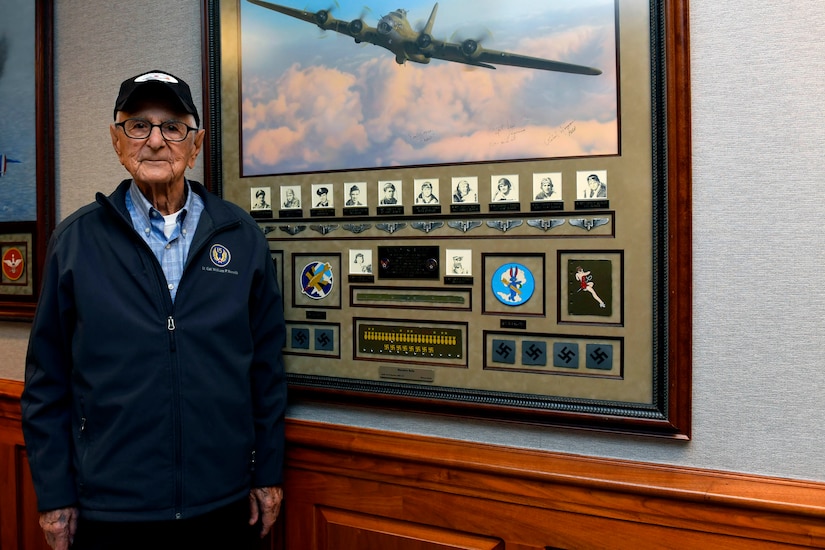 A man poses next to a painting.