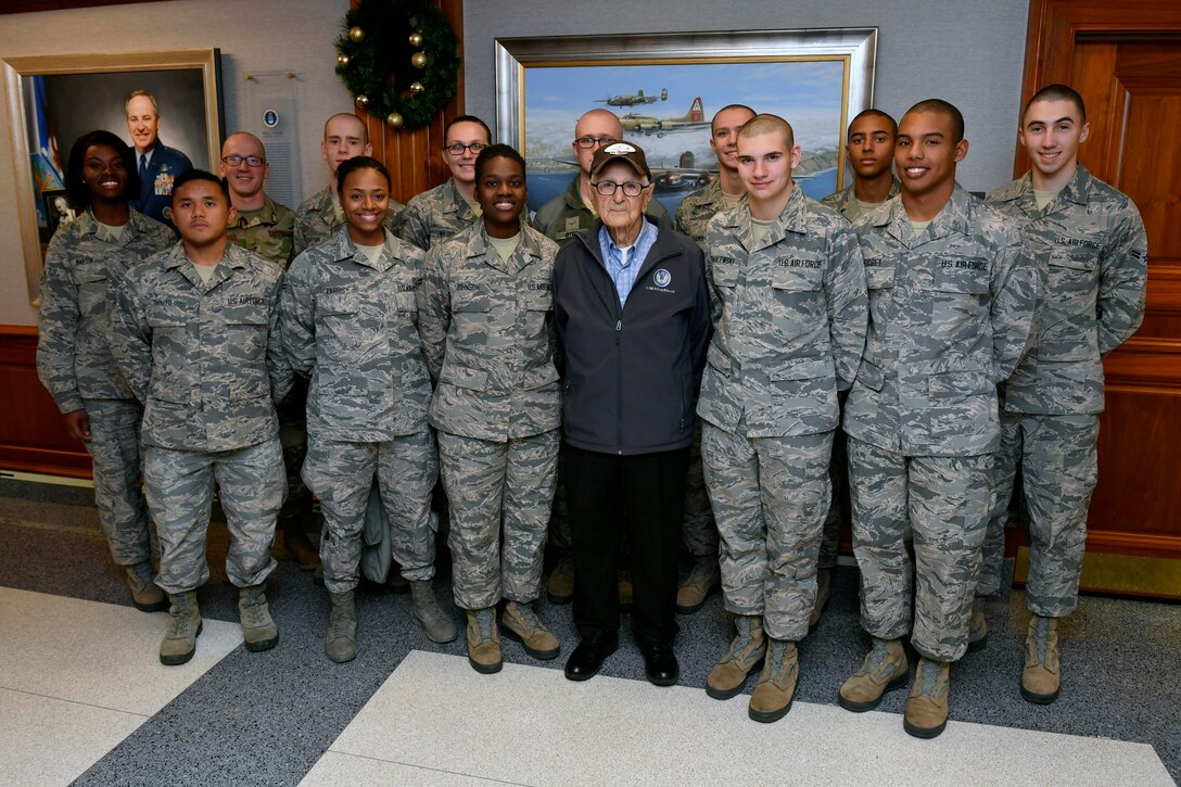 A man poses next to a group of airmen.