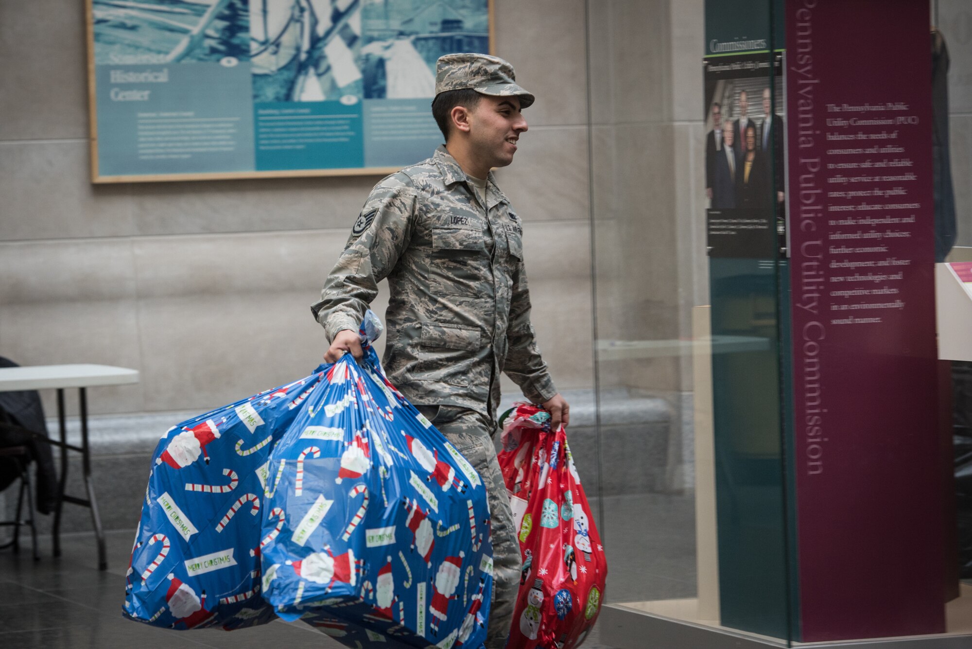 U.S. Air Force Staff Sgt. David Lopez, the wing fitness program manager with the the 193rd Special Operations Force Support Squadron, Pennsylvania Air National Guard, carries donated gifts to be loaded onto trucks for delivery, during the 30th Annual Holiday Wish Program.