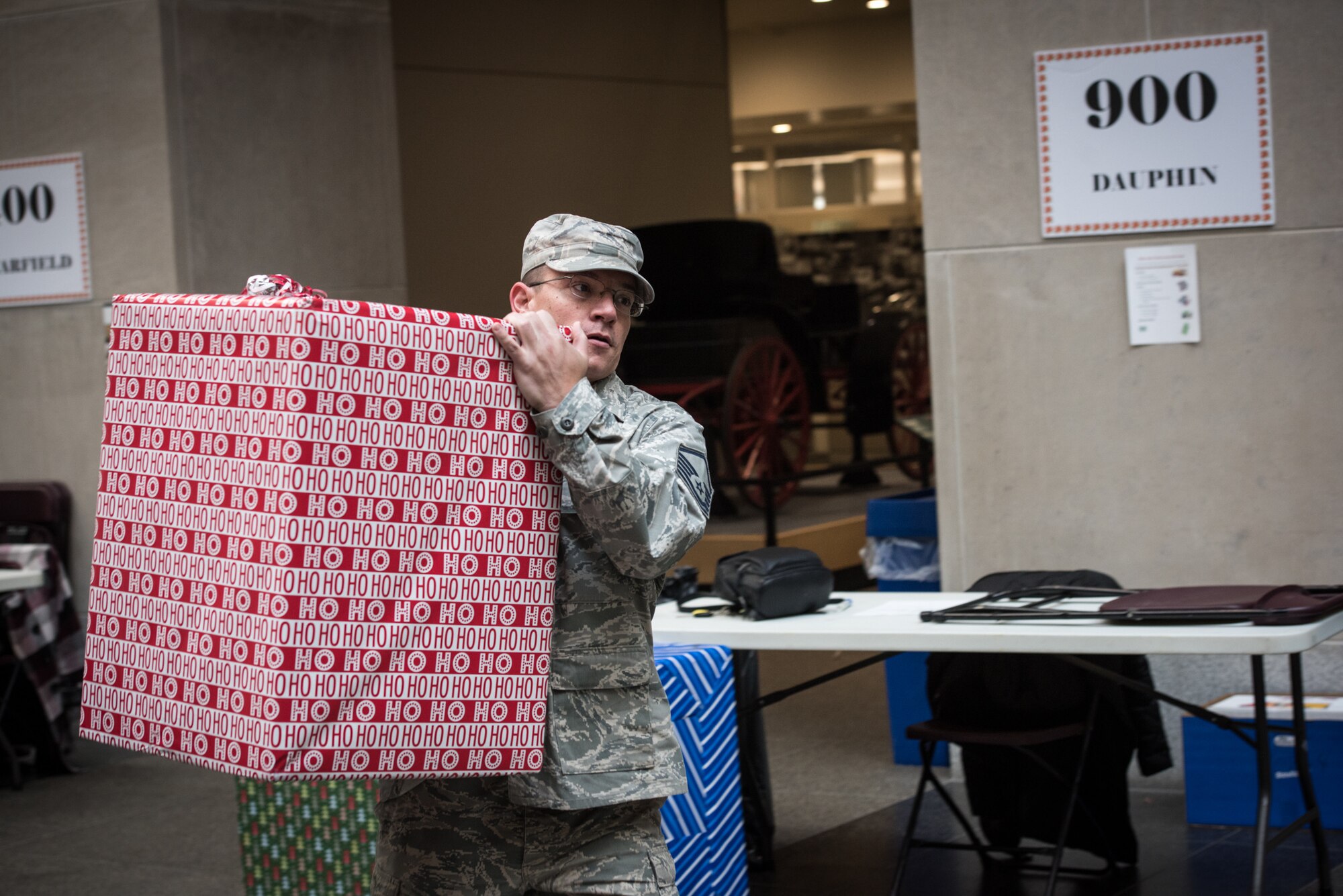 U.S. Air Force Airman Master Sgt. Matt Schwartz, a public affairs specialist with the 193rd Special Operations Wing, Pennsylvania Air National Guard, carries a box of donated-gifts to be loaded onto a truck, during the 30th Annual Holiday Wish Program.