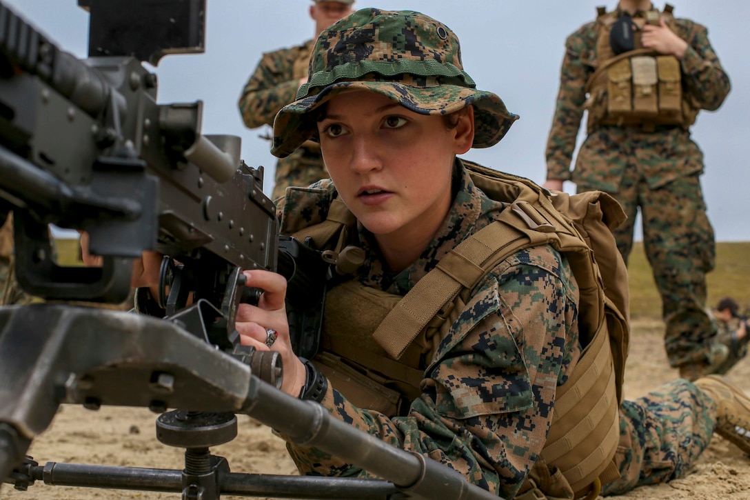 A Marine lies on the ground pointing a weapon.