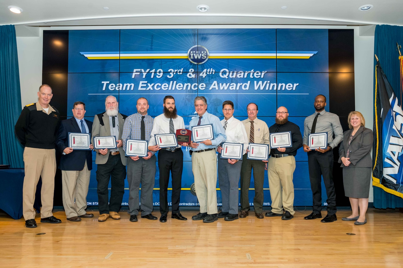 Members of the NSWC IHEODTD joint Mark 45 Team receive a PEO IWS Team Excellence Award for fiscal year 2019 3rd and 4th quarters. Pictured left to right: Rear Adm. Douglas W. Small, Program Executive Officer for Integrated Warfare Systems; NSWC IHEODTD employees David Culhane, Larry Dulin, Jesse Hitch, Drew Howells, Gregg LaFave, David Pipes, Gary Williams, Jared Wood, Lamar Anderson; and Jill Boward, Executive Director, Program Executive Office for Integrated Warfare Systems. Not pictured: Shane Hanna, Stephen Smith, John Parkes, Christopher Mahony and Zachery Rutledge. (U.S. Navy photo)