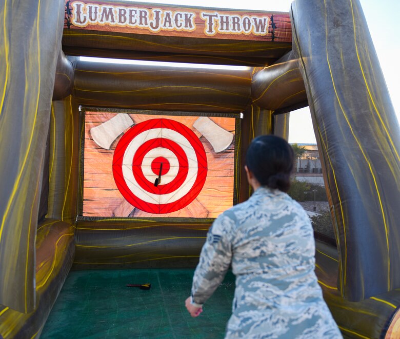 An airman throws a toy axe at an inflatable target.