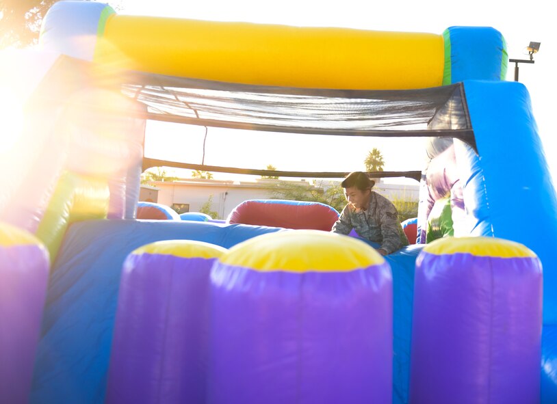 an airman plays in inflatable obstacle course
