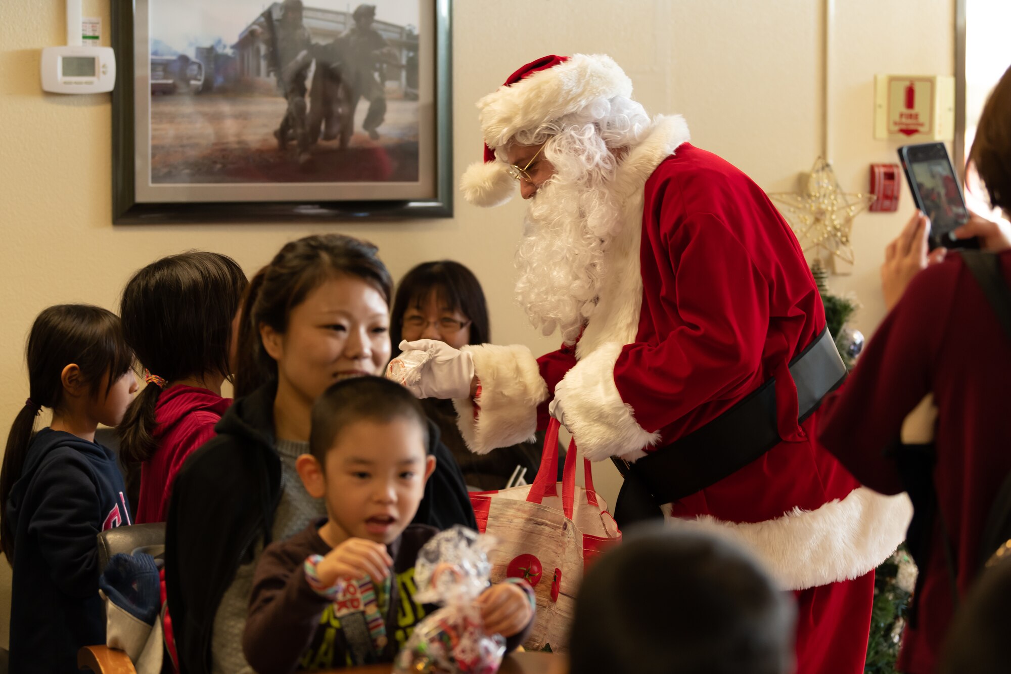 Santa Claus hands out candy to Okinawan children during the 18th Wing Tinsel Town event at Kadena Air Base, Japan, Dec. 14, 2019. Tinsel Town is an annual event where the local community and service members have a chance to get together and share the holiday spirit with music, food, theme park-style rides, and even snow. (U.S. Air Force photo by Senior Airman Matthew Seefeldt)