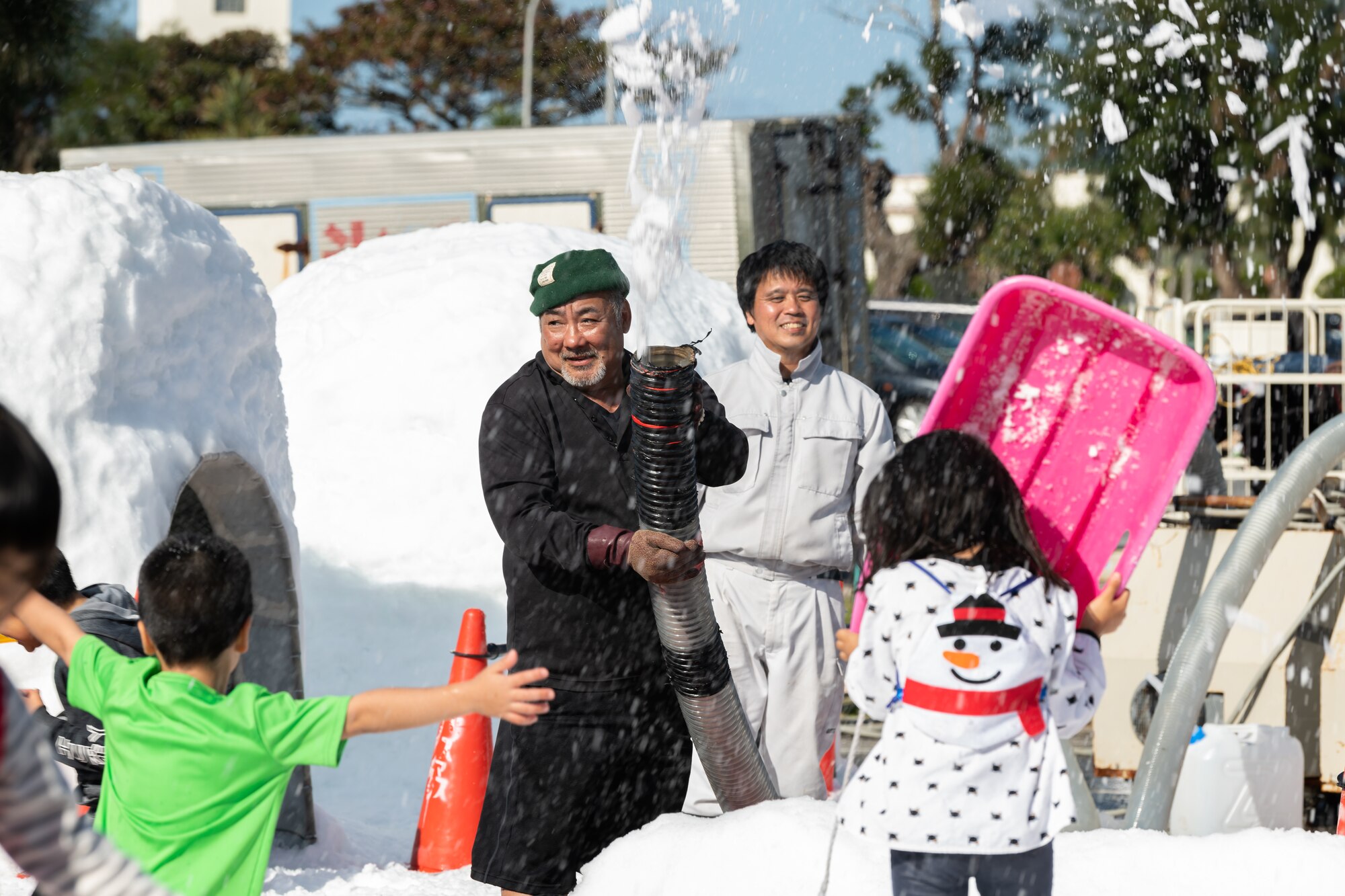 A man creates a snow park for children to play in during the 18th Wing Tinsel Town event at Kadena Air Base, Japan, Dec. 14, 2019. Children were able to sled, build snowmen, and explore igloos. (U.S. Air Force photo by Senior Airman Matthew Seefeldt)