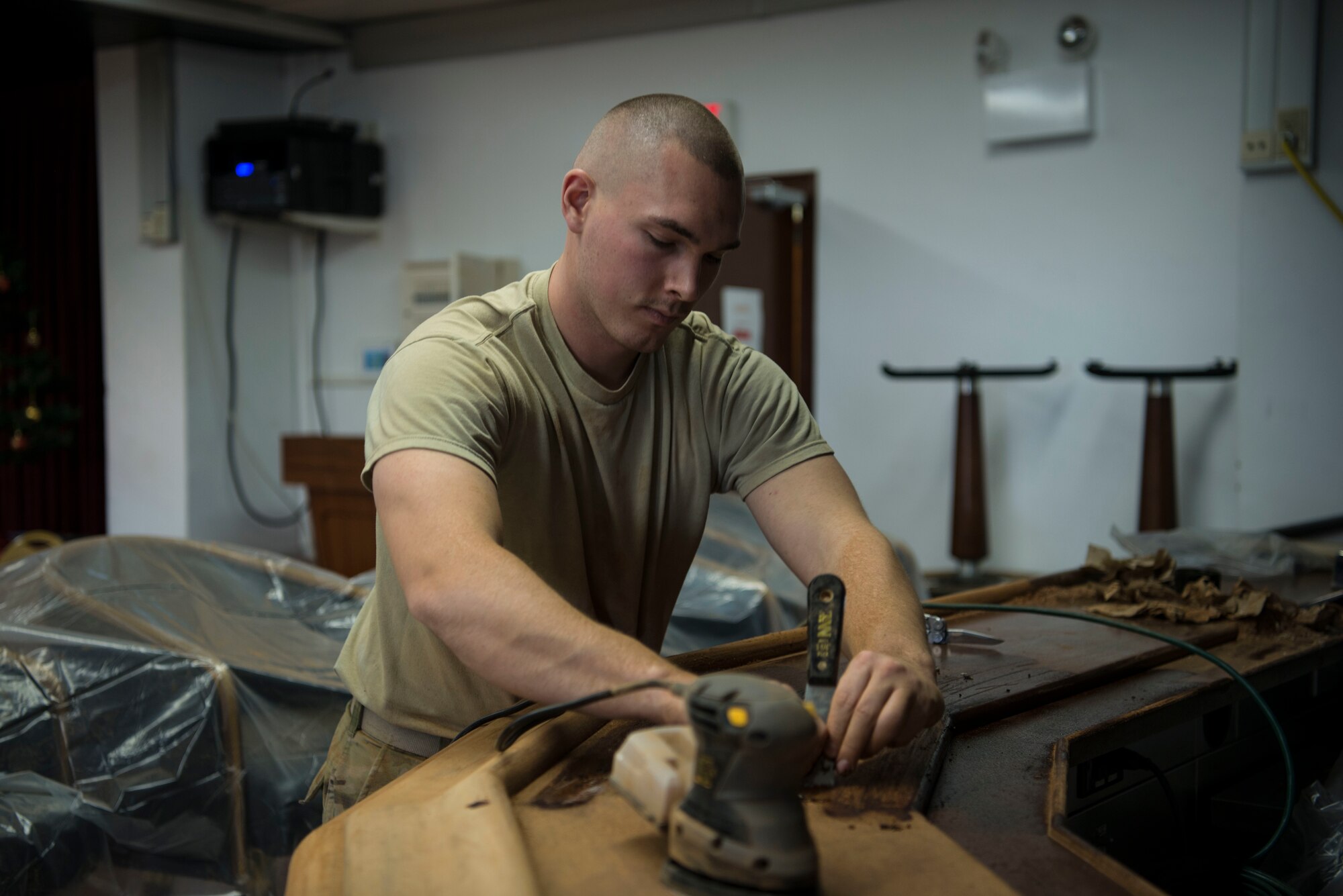 U.S. Air Force Senior Airman Brandon Smith, 786th Civil Engineer Squadron structural journeyman, refurbishes a community center bar table at Morón Air Base, Spain, Dec. 11, 2019. (U.S. Air Force photo by Senior Airman Sara Voigt)