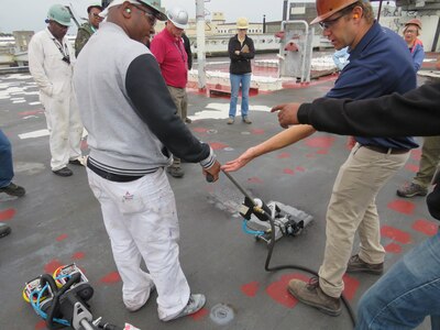 Code 970 Mechanic Dionisio Dillard uses the Standup Abrading Machine (SAM) on the USS McKee (AS-41). The Standup Abrading Machine is an ergonomic device that is able to smooth out rough surfaces, including non-skid surfaces.