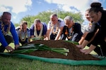 Representatives of the Pacific Energy Assurance Renewables Laboratory place their hands on a symbolic mound of earth during a blessing ceremony Dec. 17, 2019, at Joint Base Pearl Harbor-Hickam, Hawaii. The ceremony honored a microgrid project designed to provide new layers of energy assurance and self-sustaining power sources to the 154th Wing.