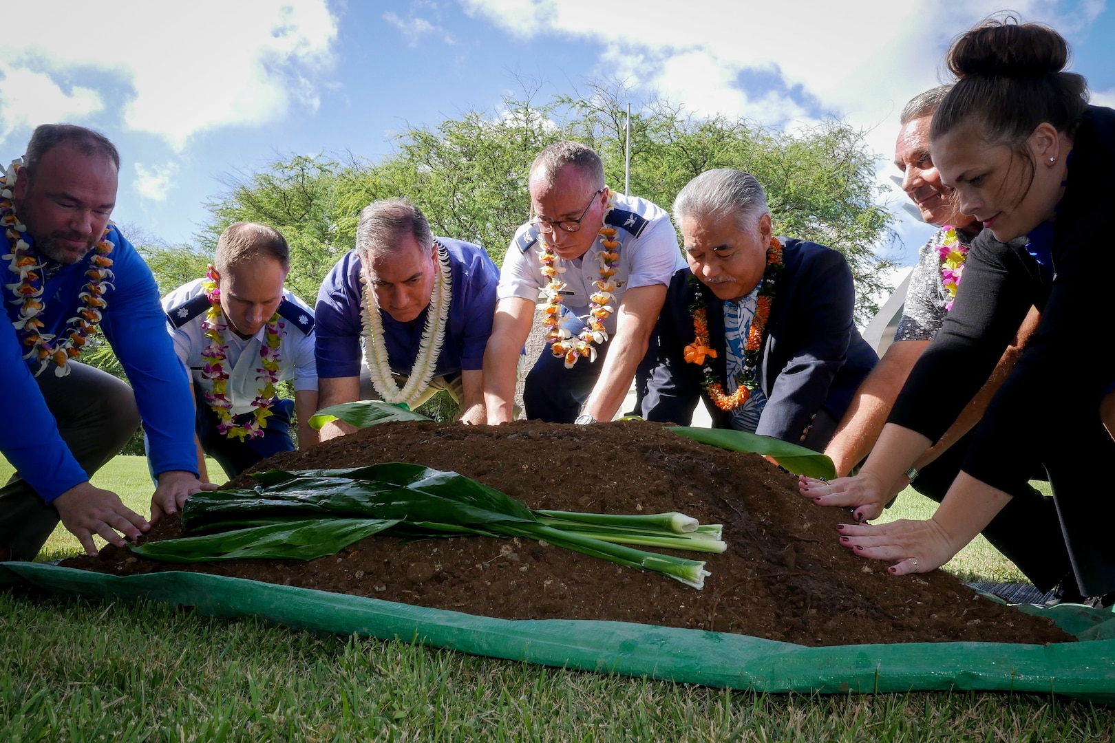 Representatives of the Pacific Energy Assurance Renewables Laboratory place their hands on a symbolic mound of earth during a blessing ceremony Dec. 17, 2019, at Joint Base Pearl Harbor-Hickam, Hawaii. The ceremony honored a microgrid project designed to provide new layers of energy assurance and self-sustaining power sources to the 154th Wing.