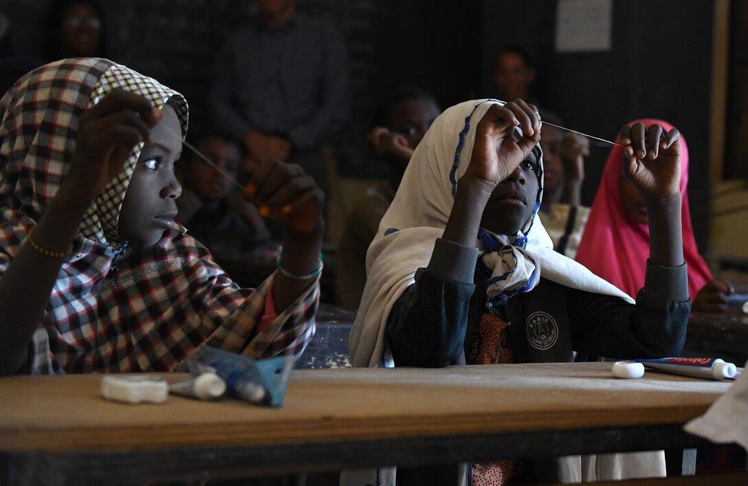 Local school children learn how to floss during a dental hygiene course in the village of Tsakatalam, Niger, Dec. 14, 2019. The U.S. Army 443rd Civil Affairs Battalion Civil Affairs Team 219 deployed to Nigerien Air Base 201 partnered with local Agadez city dentist, Dr. Mahaman Aicha, to teach the Tsakatalam Primary School students for the first time how to properly brush and floss their teeth and the importance of good oral health. (U.S. Air Force photo by Staff Sgt. Alex Fox Echols III)