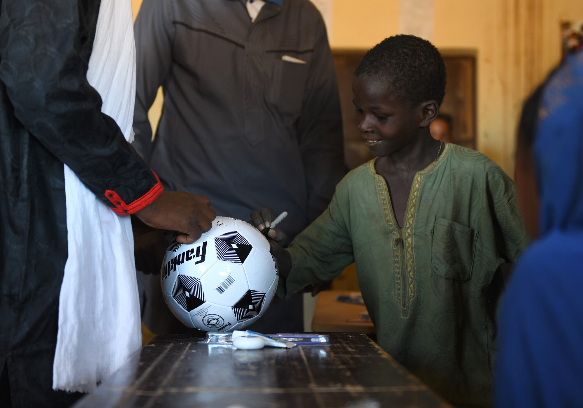 A local student signs his name on a soccer ball in commemoration of the first ever dental hygiene course in the village of Tsakatalam, Niger, Dec. 14, 2019. The U.S. Army 443rd Civil Affairs Battalion Civil Affairs Team 219 deployed to Nigerien Air Base 201 partnered with local Agadez city dentist, Dr. Mahaman Aicha, to teach the Tsakatalam Primary School students for the first time how to properly brush and floss their teeth and the importance of good oral health. (U.S. Air Force photo by Staff Sgt. Alex Fox Echols III)