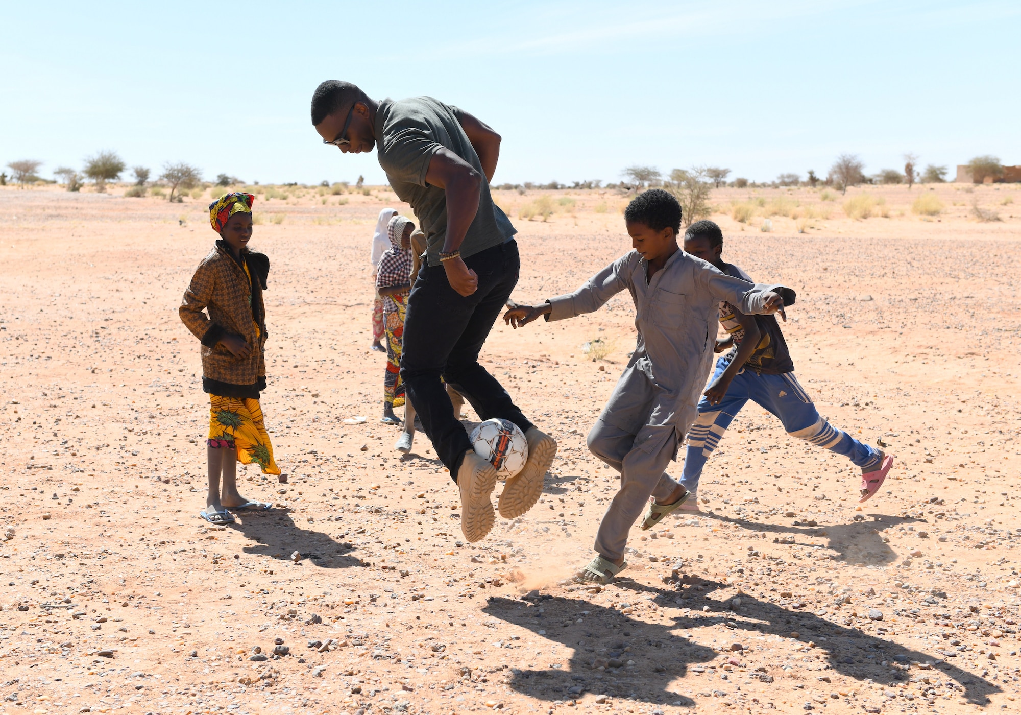 U.S. Air Force Senior Airman Ciscero Warren, 724th Expeditionary Air Base Squadron Logistics Readiness Flight fuels distribution technician, plays soccer with local school children after a dental hygiene course in the village of Tsakatalam, Niger, Dec. 14, 2019. The U.S. Army 443rd Civil Affairs Battalion Civil Affairs Team 219 deployed to Nigerien Air Base 201 partnered with local Agadez city dentist, Dr. Mahaman Aicha, to teach the Tsakatalam Primary School students for the first time how to properly brush and floss their teeth and the importance of good oral health. (U.S. Air Force photo by Staff Sgt. Alex Fox Echols III)