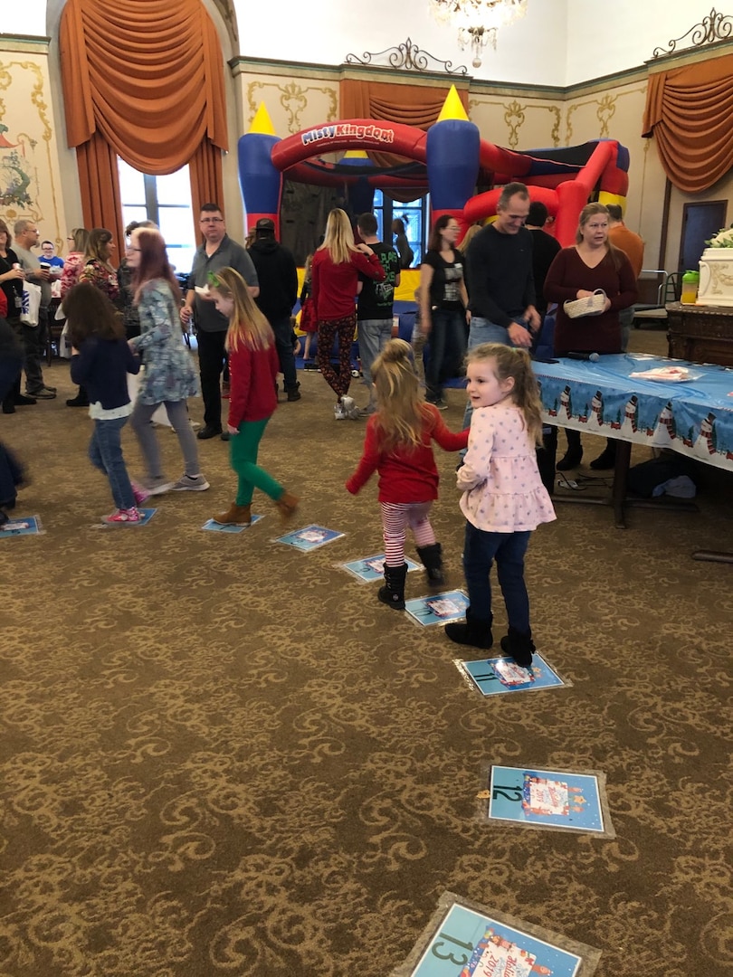 Kids walking in a circle on papers with a bounce house in the background.