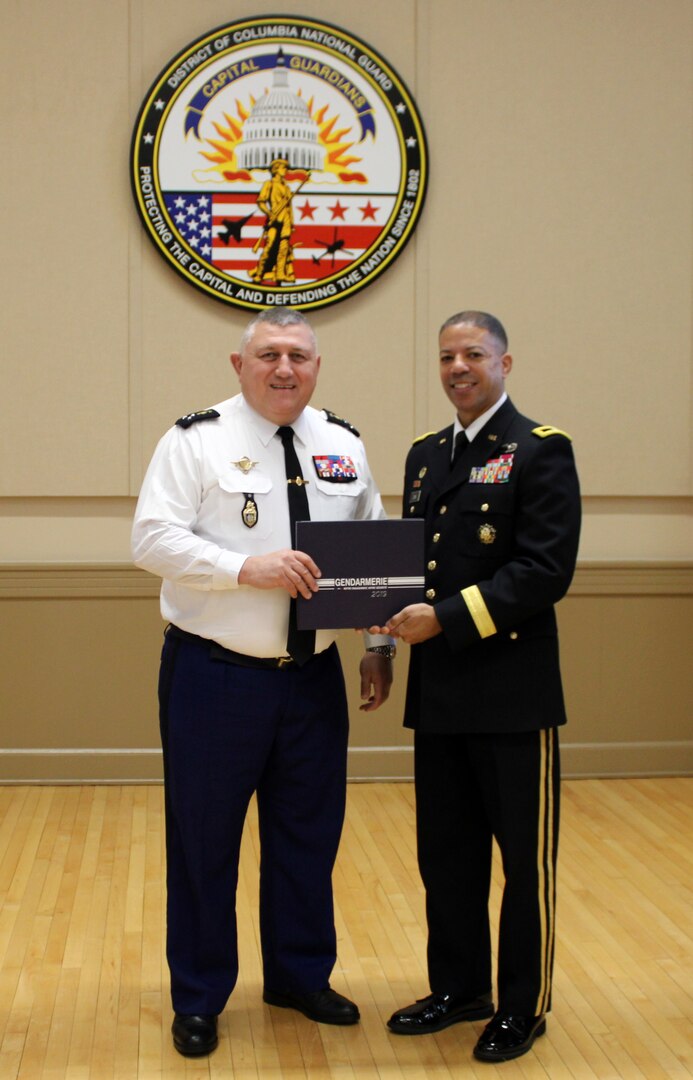 Maj. Gen. Olivier Kim, Chief of the French Gendarmerie Reserves Command, presents a historical photobook to Brig. Gen. Aaron R. Dean II, the Adjutant General of the District of Columbia National Guard, at the conclusion of his visit to the DCNG Armory.