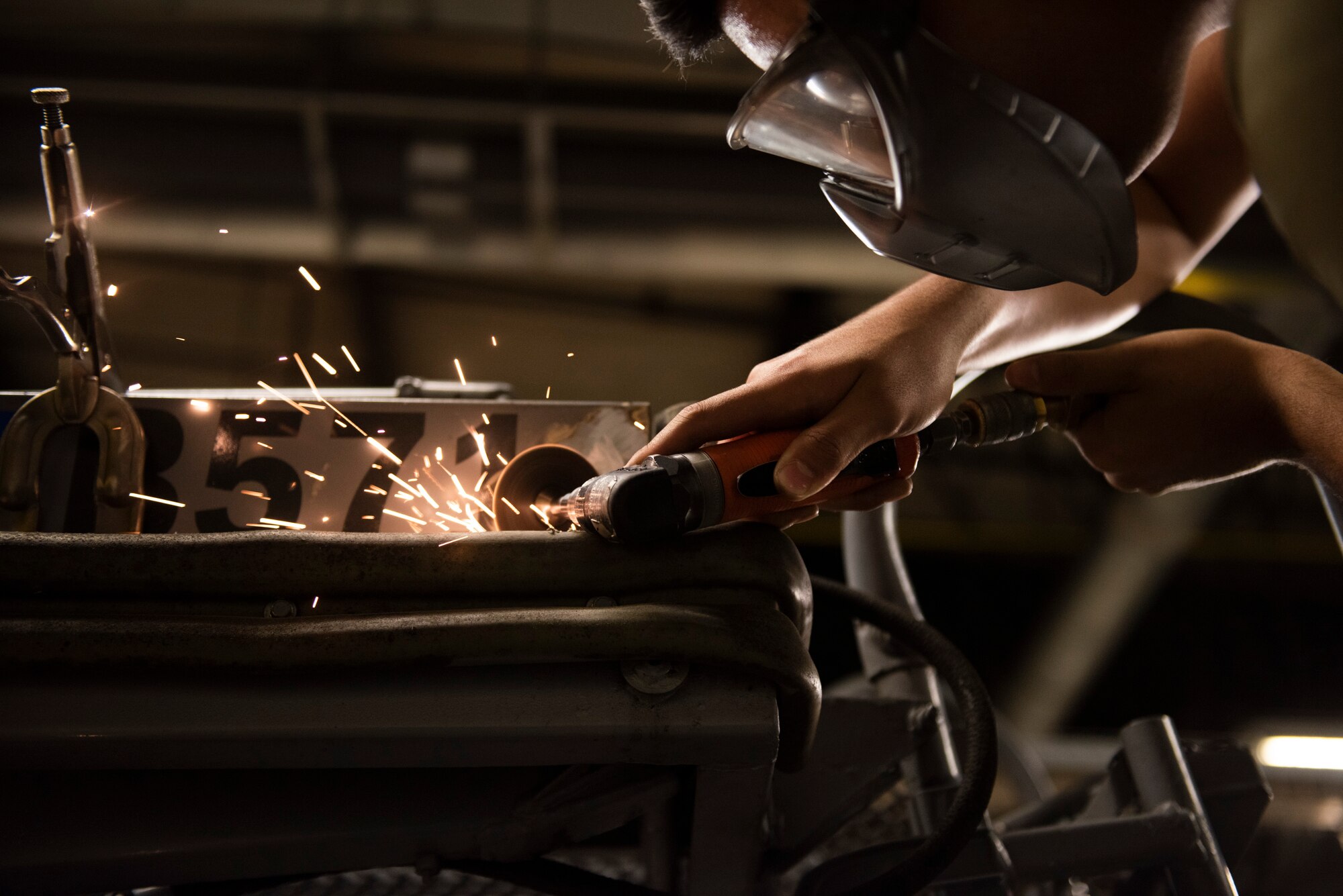 A photo of an Airman sawing at metal