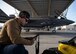 An Airman holds a tablet with an F-35A Lightning II fighter jet in the background.