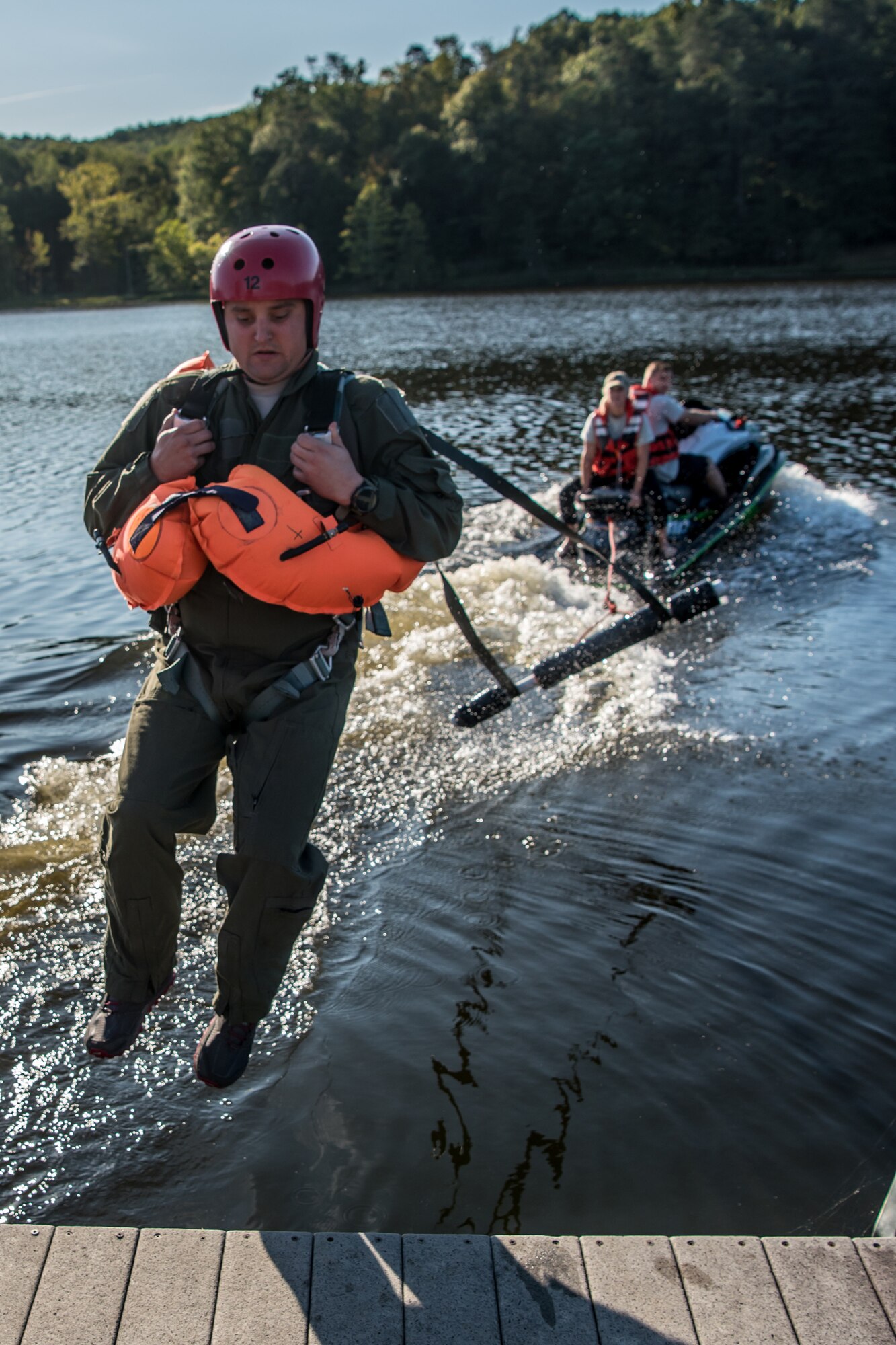 Tech. Sgt. Daniel Fuller, a loadmaster for the Kentucky Air National Guard’s 165th Airlift Squadron, is pulled across the water at Camp Crooked Creek in Shepherdsville, Ky., Sept. 14, 2019, by a personal watercraft as part of routine survival training. The exercise is designed to simulate what could happen to aircrew members who’ve parachuted into water when the wind catches their open chutes and drags them across the surface, posing the risk of drowning. (U.S. Air National Guard photo by Staff Sgt. Joshua Horton)