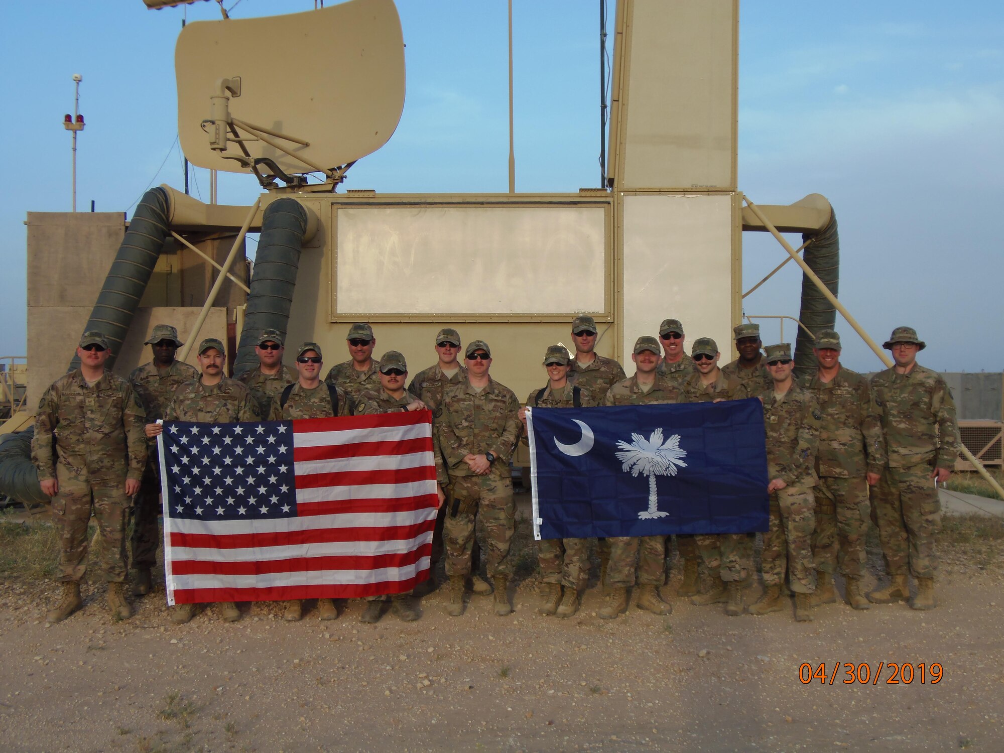 U.S. Airmen assigned to the South Carolina Air National Guard's 245th Air Traffic Control Squadron pose with two flags during their deployment to Al Asad Airbase in Iraq, April 30, 2019. (U.S. Air National Guard courtesy photo)