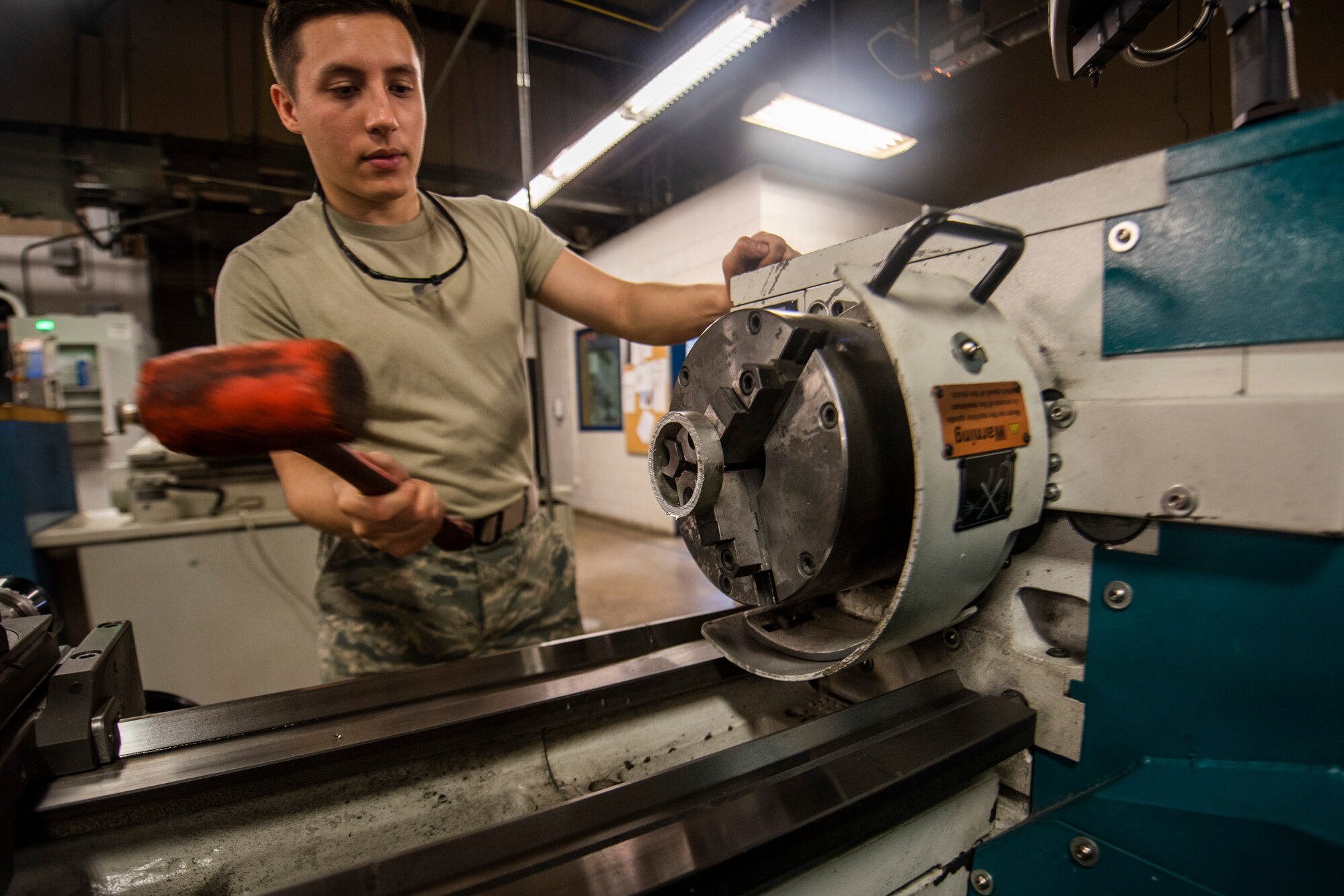 A photo of an Airman hitting a bushing with a rubber mallet.