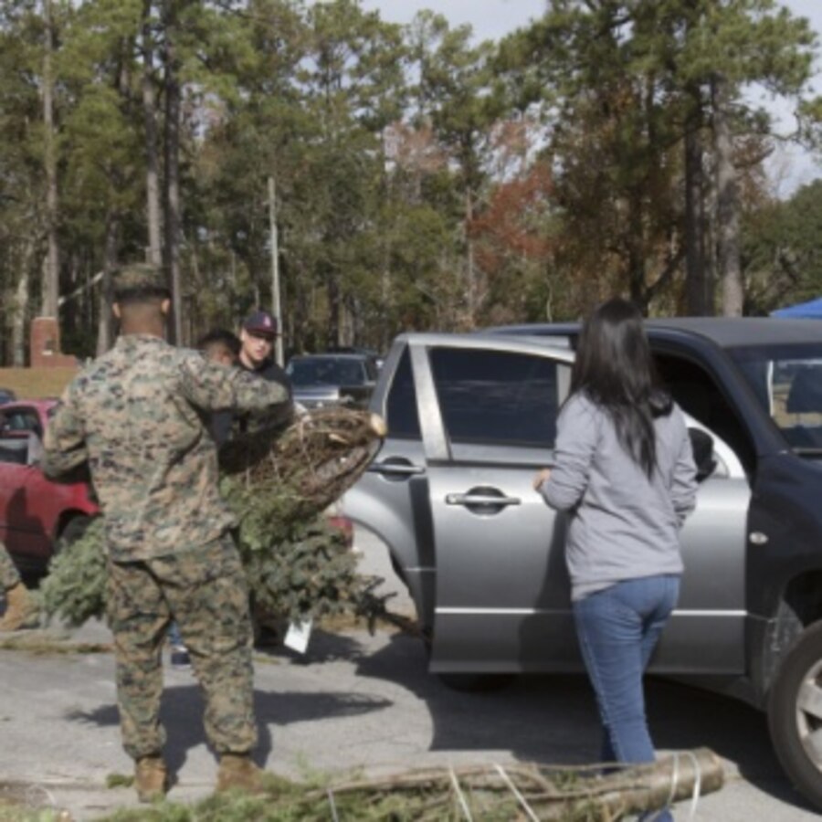 U.S. Marine volunteers tie a tree to the roof of a car during the 14th annual Trees for Troops event at Marine Corps Air Station Cherry Point, North Carolina, Dec. 6, 2019. Volunteers with the Single Marine Program helped distribute more than 400 free trees to service members and their families as a symbol of brotherhood and appreciation for the community during the holiday season. (U.S. Marine Corps photo by Cpl. Alexandra Amor Santos Arambulo)