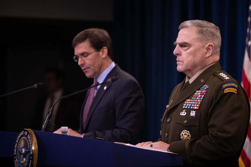 A civilian speaks and a military officer looks forward while both men stand behind podiums.