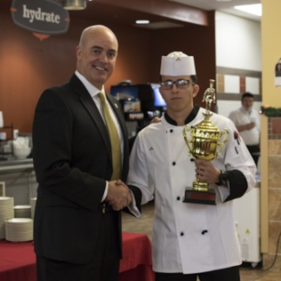 Chip Hughes, sheriff of Craven County, North Carolina, presents U.S. Marine Corps Lance Cpl. Edwin Aristizabal, a food service specialist assigned to Headquarters and Headquarters Squadron, Marine Corps Air Station (MCAS) Cherry Point, the first-place trophy at a Chef of the Quarter event at MCAS Cherry Point, North Carolina, Dec. 13, 2019. Aristilzabal, a New Jersey native, prepared an Italian meal for the judges and managed to take first-place. Aristilzabal will be moving on to compete at the 2020 Chef of the Year. (U.S. Marine Corps photo by Lance Cpl. Jacob Bertram)