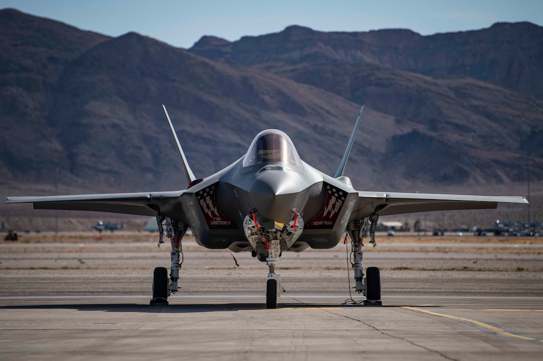 An aircraft sits on a runway with mountains in the background.